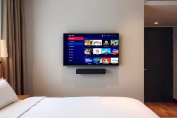 alt_text: A modern hotel room with a neatly made bed and a wall-mounted TV displaying a crisp IPTV channel guide and on-demand menu.